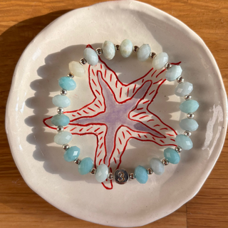 Bracelet with starfish design on a white plate on a wooden surface