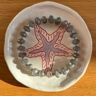 Bracelet with starfish design on a white plate on a wooden surface