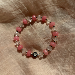 Beaded bracelet with pink and clear beads on a textured beige surface